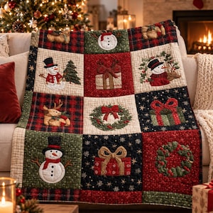 May include: A quilted throw blanket featuring a grid of nine squares with Christmas-themed appliqués including snowmen, wrapped gifts, and wreaths. The fabric displays a mix of red, green, and black plaid patterns alongside solid cream panels.