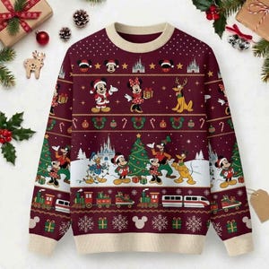 May include: A long-sleeve crewneck sweater in deep burgundy with a cream-colored collar, cuffs, and hem. The knit features a repeating Christmas pattern with Disney characters including Mickey, Minnie, Donald, Goofy, and Pluto, plus a train and castle.