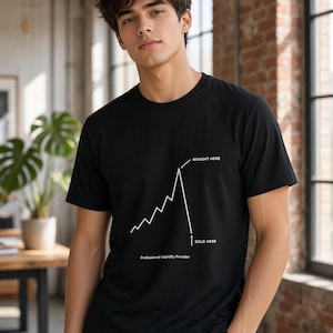 Op de afbeelding: Een zwart t-shirt met korte mouwen en een witte grafische lijn die een scherpe stijging en daaropvolgende daling toont. De tekst BOUGHT HERE wijst naar de piek, SOLD HERE naar het dieptepunt, en Professional Liquidity Provider staat onderaan.