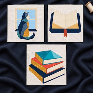 May include: Three square fabric quilt blocks featuring geometric designs. One block shows a cat sitting by a window, another displays an open book with a red bookmark, and the third depicts a stack of three books in blue, red, and yellow.