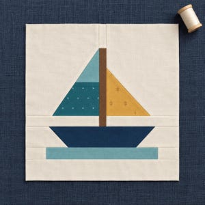 Peut inclure: Un bloc de courtepointe en tissu carré présentant un motif de voilier assemblé sur un fond crème. Le bateau possède une coque bleu foncé, un mât marron, une voile bleu sarcelle à pois blancs et une voile jaune moutarde à motifs de feuilles.