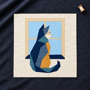 Pode incluir: Um bloco de colcha de tecido quadrado apresentando um gato feito de peças em frente a uma janela. O gato é construído com pedaços de tecido azul escuro, azul-petróleo e amarelo mostarda com pequenos padrões brancos. A moldura da janela é bege e os vidros são azul-claros.