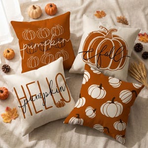 Könnte beinhalten: Vier quadratische Kissen mit Kürbismotiven. Eines ist rostorange mit weißen Kürbisumrissen und dem Text pumpkin. Eines ist cremefarben mit einem großen orangefarbenen Kürbis und dem Text fall. Eines ist cremefarben mit dem Text HELLO pumpkin. Eines ist orange mit weißen Kürbissen.