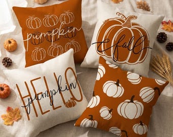 May include: Four square throw pillows featuring pumpkin designs. One is burnt orange with white pumpkin outlines and the text pumpkin. One is cream with a large orange pumpkin and the text fall. One is cream with the text HELLO pumpkin. One is orange with white pumpkins.