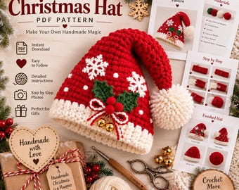 Op de afbeelding: Een rood-witte gehaakte kerstmuts met witte sneeuwvlokmotieven, een crèmekleurige pompon en een hulstversiering met twee kleine gouden belletjes. De afbeelding bevat gedrukte patrooninstructies, bollen garen en een cadeau met een hartvormig label.