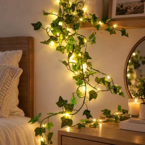 Peut inclure: Une guirlande de feuilles de lierre artificielles vertes entrelacées avec des guirlandes lumineuses LED blanc chaud. La vigne présente des formes et des textures de feuilles réalistes, avec des lumières réparties dans le feuillage.