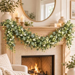 Peut inclure: Une guirlande décorative composée de feuilles d'eucalyptus vertes et de petites fleurs blanches, drapée sur une cheminée en bois. La guirlande présente un feuillage et des fleurs réalistes, créant un aspect luxuriant et superposé.