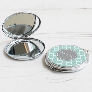 May include: A silver compact mirror with a teal and white geometric pattern and the name "Jessica" in a grey circle.