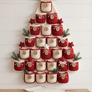 May include: A wall-hanging advent calendar shaped like a Christmas tree, crafted from cream and red crocheted pockets. Each pocket features a round wooden tag numbered one through twenty-five, accented with small crocheted stars and pine sprigs.