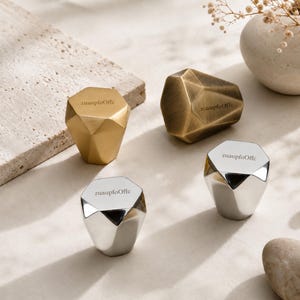 May include: Four geometric cabinet knobs with a faceted, diamond-like shape. Two knobs have a polished gold finish, and two have a polished silver finish. Each knob features the text "zuaupfoOffc" printed in a small, dark font on the top surface.