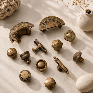 May include: A collection of antique brass-toned cabinet hardware including various knobs, T-bar pulls, and semi-circular handles. Each piece features the text "zuaupfoOffc" and displays distinct textures such as hammered, geometric, and smooth finishes.