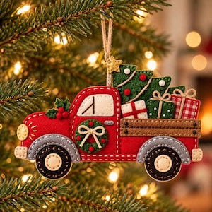 May include: A felt Christmas tree ornament shaped like a red pickup truck. The truck features grey fenders, black wheels, a green wreath on the door, and a brown truck bed carrying a green Christmas tree and three wrapped gift boxes.