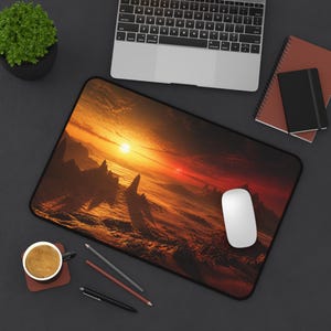 May include: A rectangular desk mat featuring a high-resolution print of a dramatic alien landscape at sunset with jagged rock formations, a glowing orange sun, and deep red shadows. The mat has a black border and a smooth surface texture.