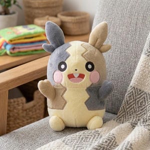 May include: A plush toy featuring a character with a yellow, tan, and dark gray color scheme. The figure has two long ears, round black eyes, pink circular cheeks, and a wide open mouth showing two white teeth. It has small arms and legs.