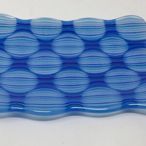 May include: A blue and white striped glass dish with a wavy edge and a textured surface. The dish is made of glass and has a unique design.