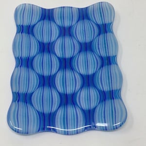 May include: A blue and white glass dish with a wavy edge and a pattern of vertical stripes that create a bubble effect.