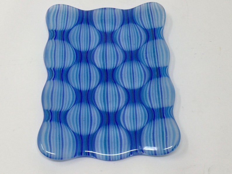 May include: A blue and white glass dish with a wavy edge and a pattern of vertical stripes that create a bubble effect.