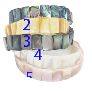 May include: A stack of five stretch bracelets made of rectangular shell tiles. The bracelets feature iridescent abalone, yellow, dark gray, white, and pale pink shell segments. The numbers 2, 3, 4, and 5 are printed in blue on the bracelets.