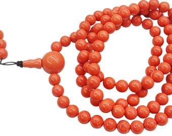 May include: A strand of smooth, round, bright orange beads arranged in a circular loop. The necklace features a larger, spherical central bead connected to a smaller, textured accent piece and a short tail of six additional orange beads.