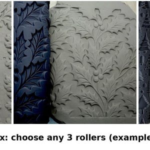 May include: Three cylindrical clay texture rollers with dark blue surfaces, each featuring a distinct embossed pattern: one with oak leaves and acorns, one with holly leaves and berries, and one with a variety of stylized pine trees.