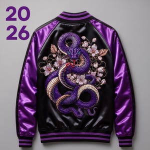 Könnte beinhalten: Eine schwarze und violette Satin-Collegejacke mit einer großen Stickerei auf der Rückseite, die eine gewundene violette Schlange umgeben von hellrosa Kirschblüten zeigt. Der Text 20 26 ist in Violett auf der oberen linken Seite aufgedruckt.
