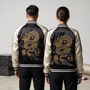 Puede incluir: Una chaqueta bomber de satén negra y crema con un dragón dorado bordado en la espalda, acompañado del texto RYU TOKYO. La chaqueta tiene mangas largas de color crema, cuerpo negro y ribetes acanalados a rayas blancas y negras en el cuello.