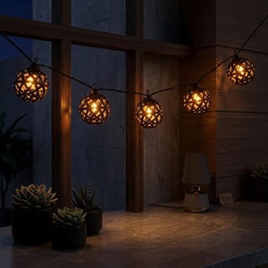 May include: A string of five spherical lights featuring a dark, woven lattice design. Each globe contains a warm, glowing bulb, connected by a thin black wire. The lights are suspended horizontally, casting a soft, amber illumination.