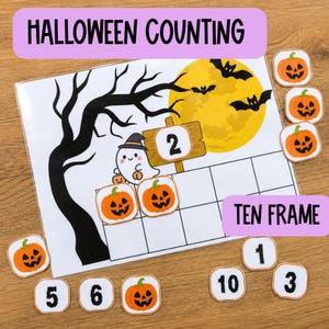 May include: A Halloween counting ten frame activity sheet featuring a black tree silhouette, a yellow moon, bats, and a ghost. The sheet includes a wooden sign with the number 2, and several square tiles depicting orange jack-o'-lanterns and numbers.