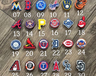 May include: A collection of thirty-three colourful rubber shoe charms featuring various Major League Baseball team logos and baseball-themed icons, each labelled with a corresponding number from 01 to 33, arranged in rows under the title Baseball.