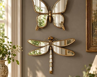 Pode incluir: Dois espelhos decorativos de parede em forma de insetos. O espelho superior é uma borboleta com molduras douradas e asas espelhadas. O espelho inferior é uma libélula com molduras douradas, asas espelhadas e uma cauda segmentada.