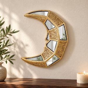 May include: A crescent moon-shaped wall mirror featuring a textured gold-tone frame with a series of geometric, multi-faceted mirror panels. The frame has a distinct, rippled, or wood-grain-like surface pattern surrounding each individual glass segment.