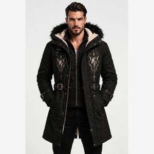May include: A black hooded parka featuring a faux fur trim, a front zipper closure, and adjustable buckled straps at the waist and cuffs. The chest area displays a symmetrical, light-colored graphic print of a stylized wolf head.