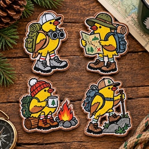 May include: Four embroidered patches featuring yellow chicks dressed as hikers. One wears a cap with binoculars, one holds a map, one sits by a campfire with a mug, and one hikes with a backpack and walking stick. Each chick wears hiking boots.