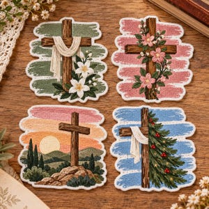 May include: Four embroidered patches featuring wooden crosses. One has white lilies and fabric, one has pink flowers, one shows a sunset landscape with a cross on a hill, and one features a pine branch with red berries and white fabric.