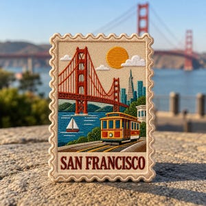May include: A rectangular embroidered patch shaped like a postage stamp featuring the Golden Gate Bridge, a cable car, and a sailboat on blue water. The text SAN FRANCISCO is stitched in dark red at the bottom against a cream background.