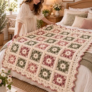 May include: A handmade crochet blanket featuring a repeating granny square pattern in shades of sage green, dusty rose, and cream. The blanket has a scalloped edge and is constructed from individual square motifs joined together with cream yarn.