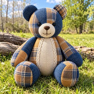 Pu&ograve; includere: Un orsacchiotto di peluche realizzato in tessuto patchwork con un motivo a quadri blu e marrone chiaro. L'orso presenta una pancia in tessuto beige tinta unita rifinita con pizzo bianco, un muso beige con naso e bocca cuciti e occhi a bottone.