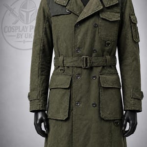 Könnte beinhalten: Ein olivgrüner, zweireihiger Trenchcoat mit Gürteltaille, mehreren Utility-Taschen, dunklen Schulterpartien und Knopfverschlüssen. Das Kleidungsstück weist eine abgenutzte Textur auf und enthält ein D-Ring-Detail an Brust und Seite.