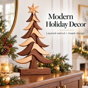 Op de afbeelding: Een decoratieve kerstboomsculptuur gemaakt van afwisselende lagen donker walnoothout en licht esdoornhout, met een ster als piek en een rechthoekige voet. De tekst luidt Modern Holiday Decor en Layered walnut + maple design.