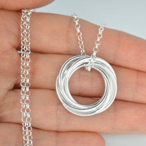 May include: Silver necklace with a pendant made of five interlocking rings.