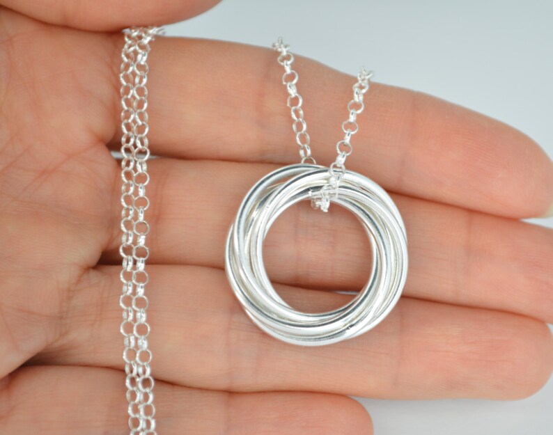 May include: Silver necklace with a pendant made of five interlocking rings.