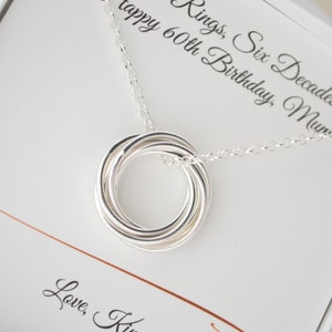 May include: A silver necklace with a six-ring pendant and a card that reads "Rings, Six Decades Happy 60th Birthday, Mum! Love, K"