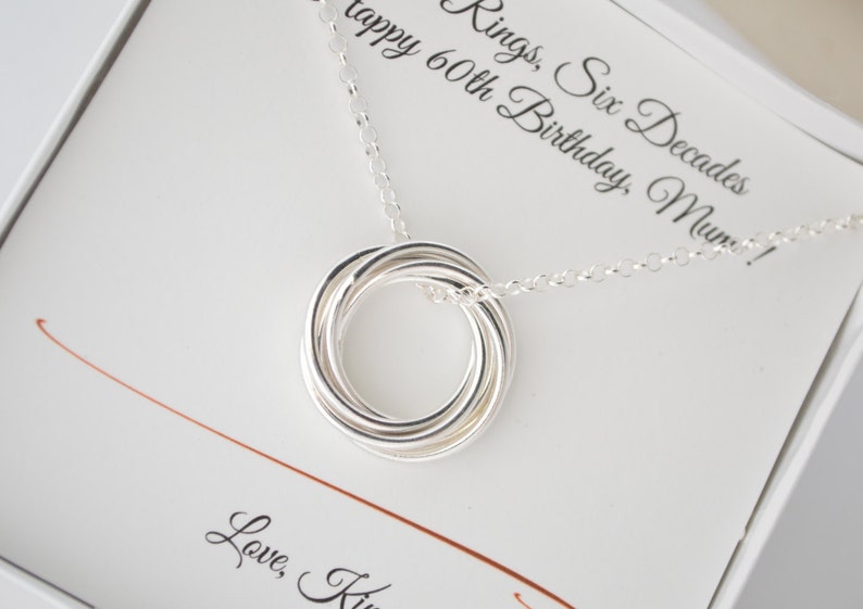 May include: A silver necklace with a six-ring pendant and a card that reads "Rings, Six Decades Happy 60th Birthday, Mum! Love, K"