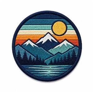 Puede incluir: Un parche bordado circular con un borde azul oscuro. El diseño muestra un paisaje con un lago en primer plano, un denso bosque de pinos azul oscuro, montañas con cumbres nevadas y un sol amarillo sobre un cielo al atardecer.