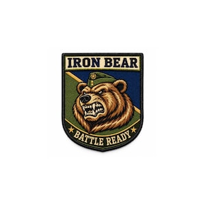 Puede incluir: Un parche bordado en forma de escudo que muestra un oso pardo con una gorra militar verde. El texto IRON BEAR aparece en la parte superior y BATTLE READY en la inferior, flanqueado por dos estrellas doradas. El fondo está dividido en azul y verde.