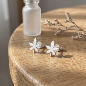 Peut inclure: Une paire de boucles d'oreilles à tige en forme de feuilles d'érable à sept pointes. Les boucles d'oreilles présentent une finition mate et brossée et comprennent des fermoirs à tige standard pour une fixation sûre, avec un design botanique.