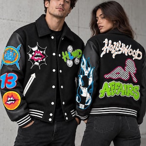 May include: Two black varsity jackets with leather sleeves and white snap buttons. The jackets feature colorful embroidered patches including lips, flames, checkerboard patterns, and text reading HLWD, 13, Hollywood, and Affairs in various fonts.