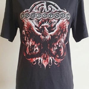 May include: Dark gray t-shirt featuring a phoenix graphic with red and white accents. The shirt has a boat neck and short sleeves. The text "CROSSFADE" is printed above the phoenix.