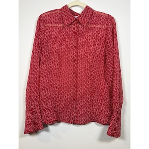 May include: A long-sleeved button-down shirt in a vibrant red color featuring a repeating white anchor pattern. The garment has a classic collar, a front button placket, and buttoned cuffs, crafted from a lightweight, semi-sheer fabric.