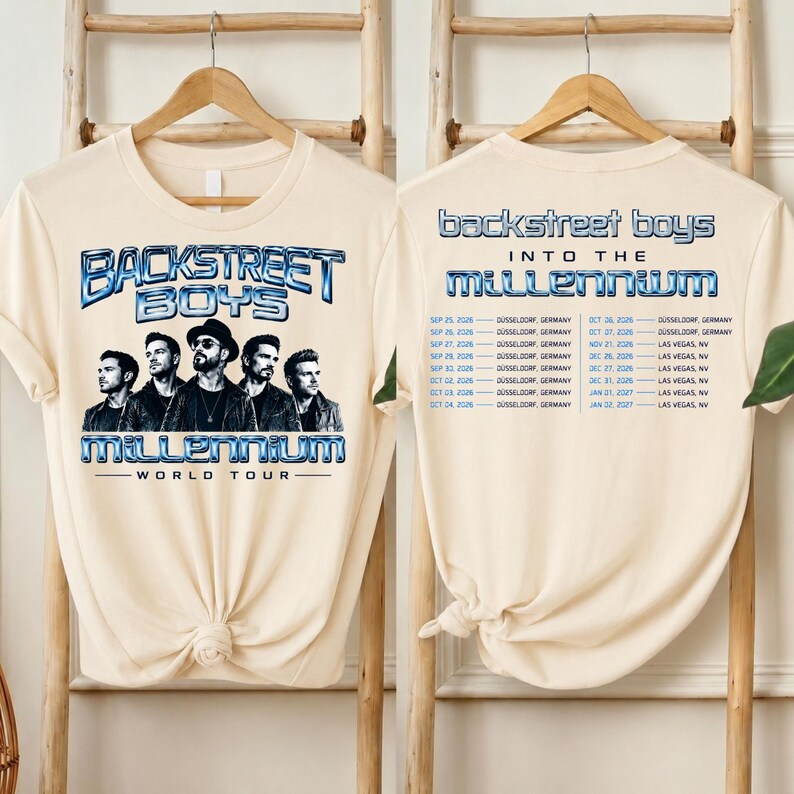 May include: A cream-colored t-shirt featuring a graphic of the Backstreet Boys with the text Backstreet Boys World Tour on the front. The back displays the text Backstreet Boys Into The Millennium with a list of tour dates in Germany and Nevada.